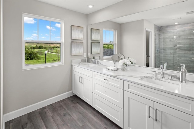 bathroom with dual bowl vanity, an enclosed shower, and wood-type flooring