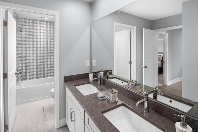 full bathroom featuring tile floors, toilet, tiled shower / bath, and double sink vanity