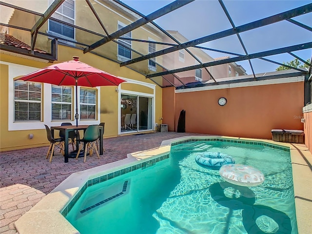 view of pool with glass enclosure and a patio