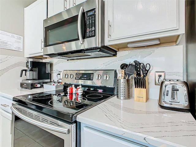 kitchen with light stone countertops, appliances with stainless steel finishes, tasteful backsplash, and white cabinetry