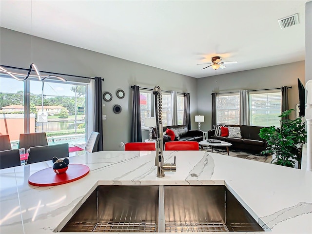 kitchen with light stone counters, ceiling fan, and sink