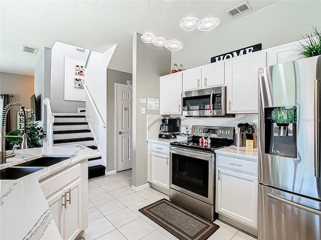 kitchen with white cabinets, decorative light fixtures, stainless steel appliances, and sink