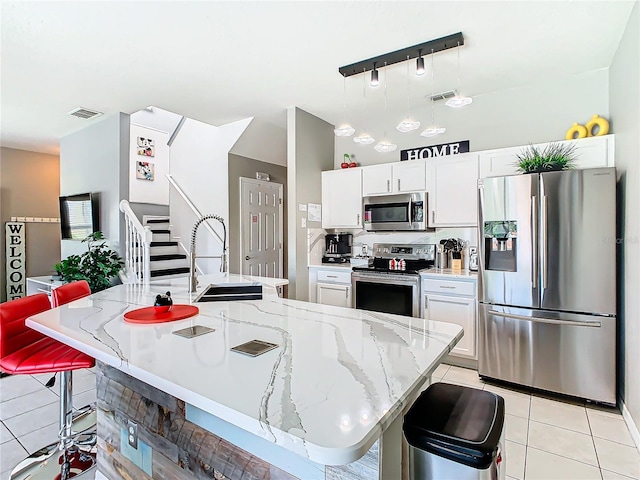 kitchen with a breakfast bar, stainless steel appliances, sink, pendant lighting, and white cabinetry