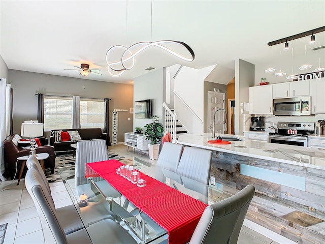 tiled dining room featuring ceiling fan, sink, and track lighting