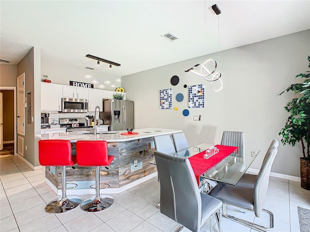 dining space featuring light tile patterned floors, rail lighting, and sink