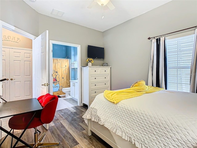 bedroom with ensuite bath, ceiling fan, multiple windows, and dark hardwood / wood-style floors