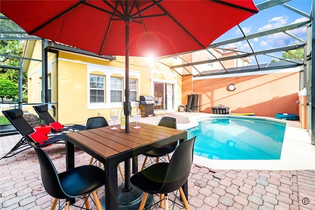 view of pool with a patio area, a grill, and glass enclosure