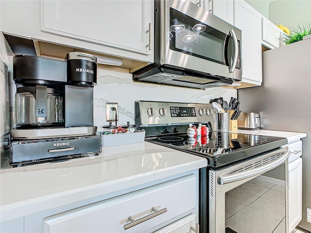 kitchen with light stone countertops, light tile patterned floors, white cabinetry, and appliances with stainless steel finishes