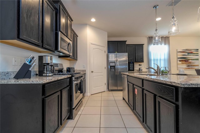 kitchen with a center island with sink, appliances with stainless steel finishes, decorative light fixtures, sink, and light tile flooring