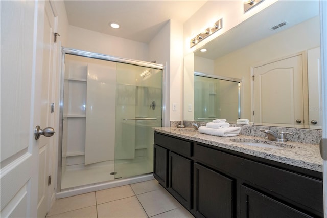 bathroom featuring oversized vanity, dual sinks, tile floors, and a shower with door