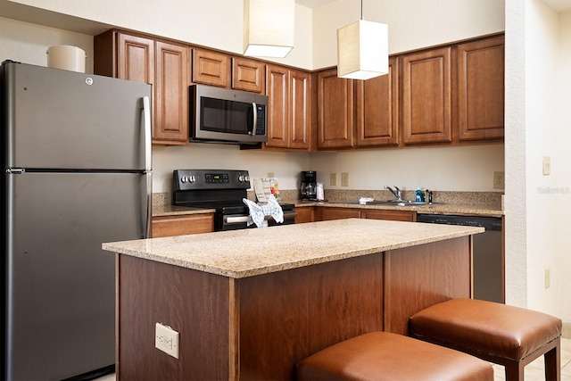 kitchen with light stone countertops, sink, a kitchen breakfast bar, pendant lighting, and appliances with stainless steel finishes