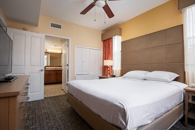 bedroom featuring tile patterned floors, ceiling fan, tile walls, and connected bathroom