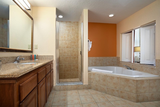 bathroom featuring plus walk in shower, a textured ceiling, vanity, and tile patterned floors