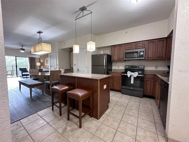 kitchen featuring ceiling fan, black appliances, light hardwood / wood-style flooring, a kitchen island, and a breakfast bar area