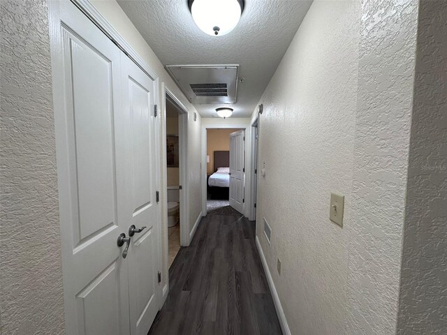 hallway with a textured ceiling and dark wood-type flooring