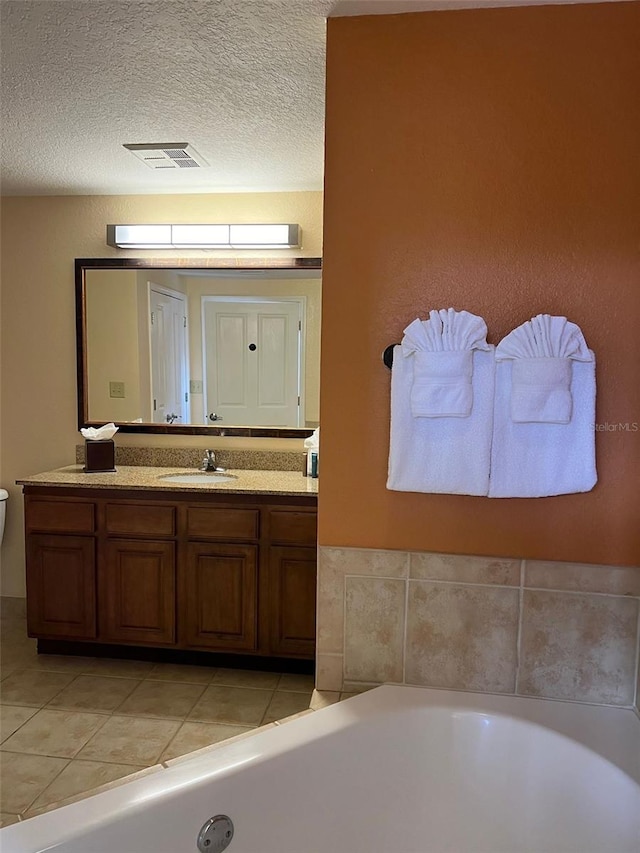 bathroom with vanity, a textured ceiling, tile patterned floors, and a bathtub