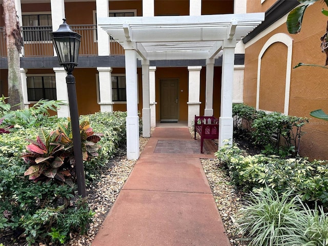 view of exterior entry with a pergola