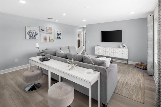 living room featuring light wood-type flooring, visible vents, baseboards, and recessed lighting