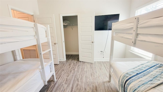 bedroom featuring a closet, a walk in closet, and wood-type flooring