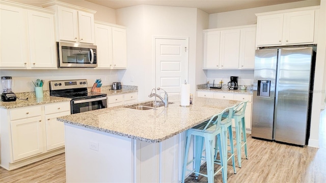 kitchen with sink, light hardwood / wood-style floors, a center island with sink, and appliances with stainless steel finishes