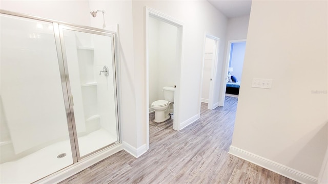 bathroom with hardwood / wood-style floors, an enclosed shower, and toilet