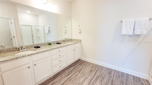 bathroom with walk in shower, double sink vanity, and wood-type flooring