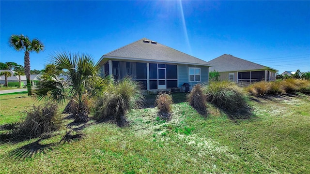 rear view of house with a yard and a sunroom