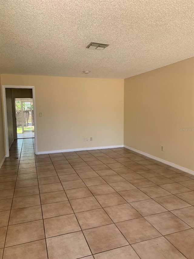 empty room with tile floors and a textured ceiling