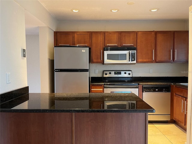 kitchen featuring light tile patterned floors, appliances with stainless steel finishes, and dark stone counters