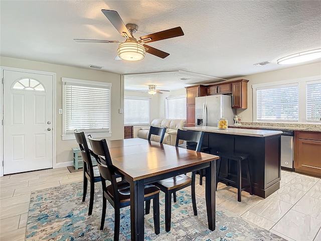 dining room featuring light hardwood / wood-style floors, a textured ceiling, and ceiling fan