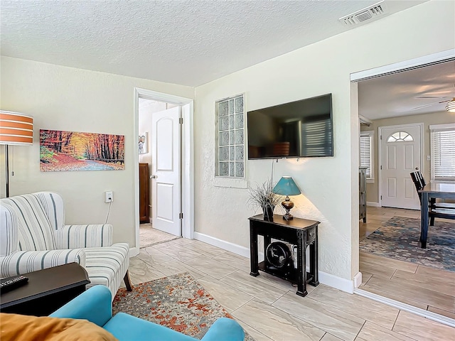 living room featuring a textured ceiling and ceiling fan