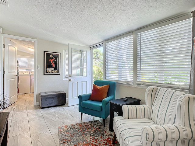 sitting room with washing machine and clothes dryer, light tile patterned floors, and a textured ceiling