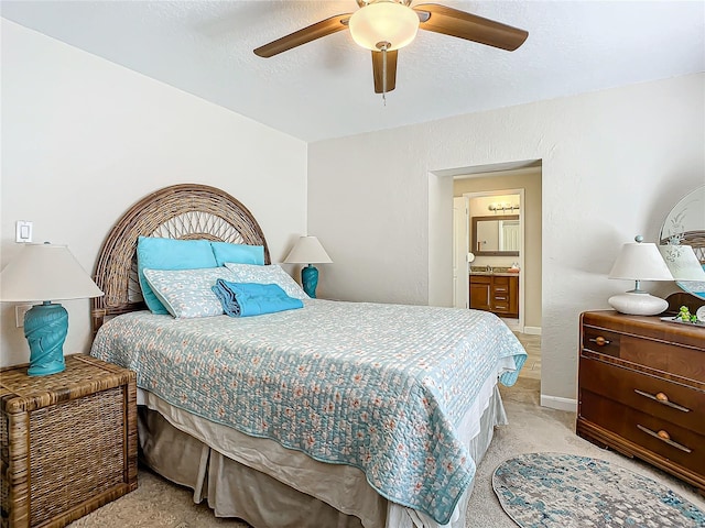 bedroom featuring ceiling fan, light colored carpet, ensuite bath, and a textured ceiling