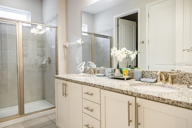 bathroom with a shower with shower door, double sink vanity, and tile floors