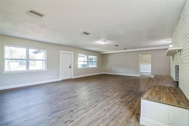 unfurnished living room with a healthy amount of sunlight, a fireplace, wood-type flooring, and a textured ceiling