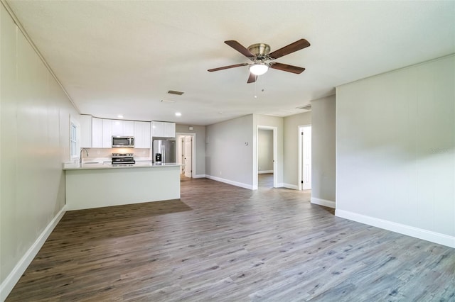 unfurnished living room featuring ceiling fan, sink, and wood-type flooring