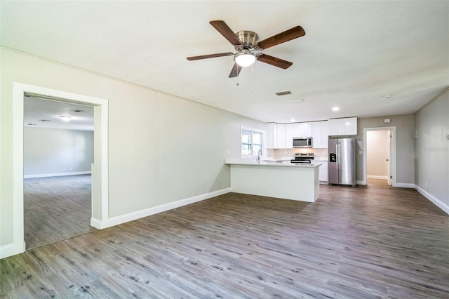 kitchen featuring white cabinets, kitchen peninsula, ceiling fan, appliances with stainless steel finishes, and wood-type flooring