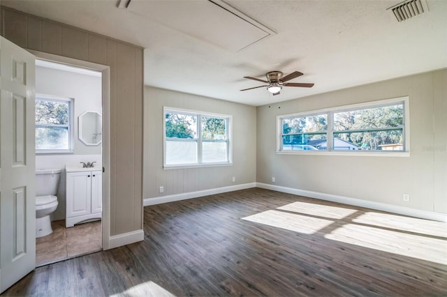 unfurnished bedroom with a textured ceiling, connected bathroom, dark hardwood / wood-style floors, and ceiling fan