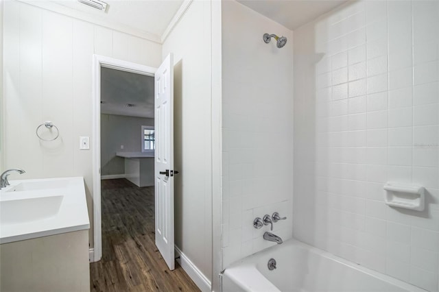 bathroom with wood-type flooring, vanity, and tiled shower / bath