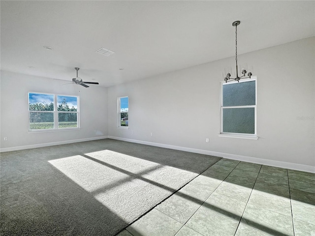 empty room featuring ceiling fan with notable chandelier