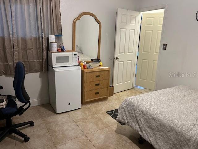 tiled bedroom featuring white refrigerator