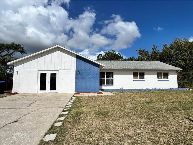 7313 Cabor Ct, Orlando, FL 32818 - view of front of house featuring board and batten siding, french doors, a shingled roof, and a front lawn