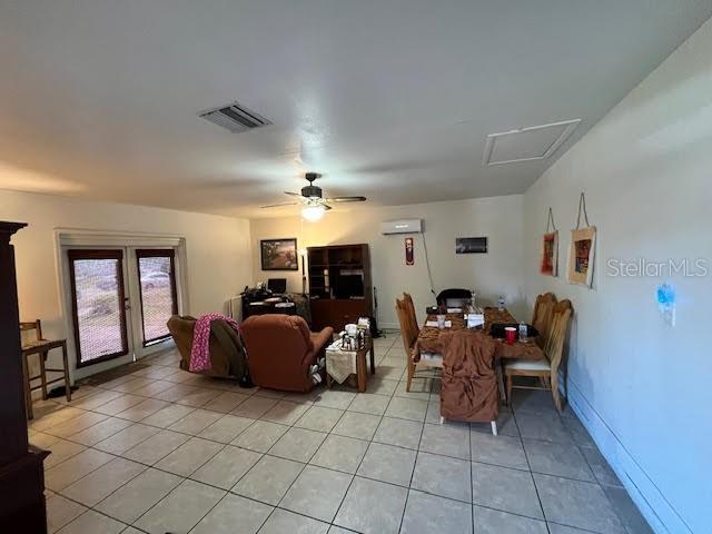 tiled dining space featuring a wall mounted air conditioner and ceiling fan