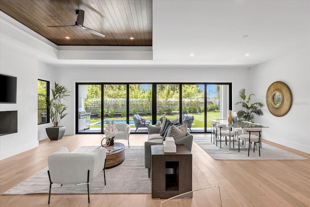 living room featuring a multi sided fireplace, ceiling fan, and light wood-type flooring