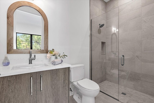 bathroom with a shower with shower door, vanity, and toilet