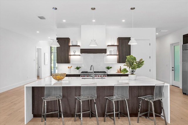 kitchen featuring a large island with sink, light hardwood / wood-style floors, and a kitchen bar