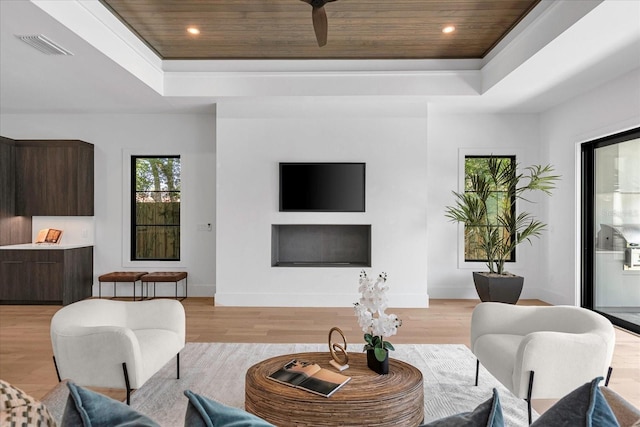 living room with a tray ceiling, wood ceiling, and light hardwood / wood-style flooring