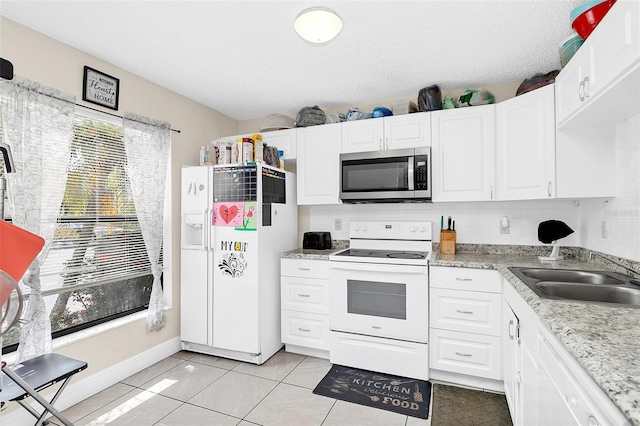 kitchen featuring a healthy amount of sunlight, white appliances, light tile floors, and tasteful backsplash