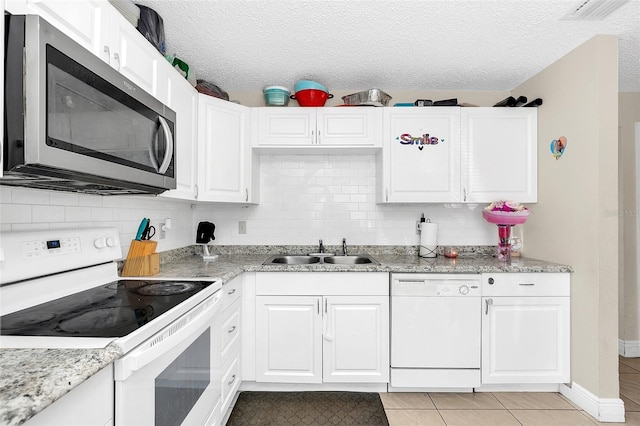 kitchen with backsplash, white cabinetry, sink, white appliances, and light tile floors