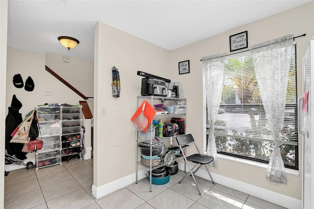 miscellaneous room with light tile flooring and a textured ceiling